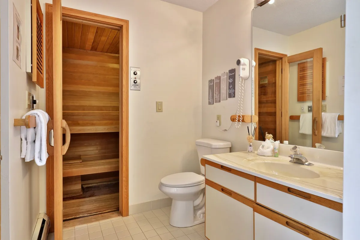 A modern, inviting sauna area with warm wood finishes and an adjacent vanity with sink. The tranquil atmosphere is ideal for relaxation after a day of outdoor adventure, offering a glimpse into the spa-like wellness facilities available.