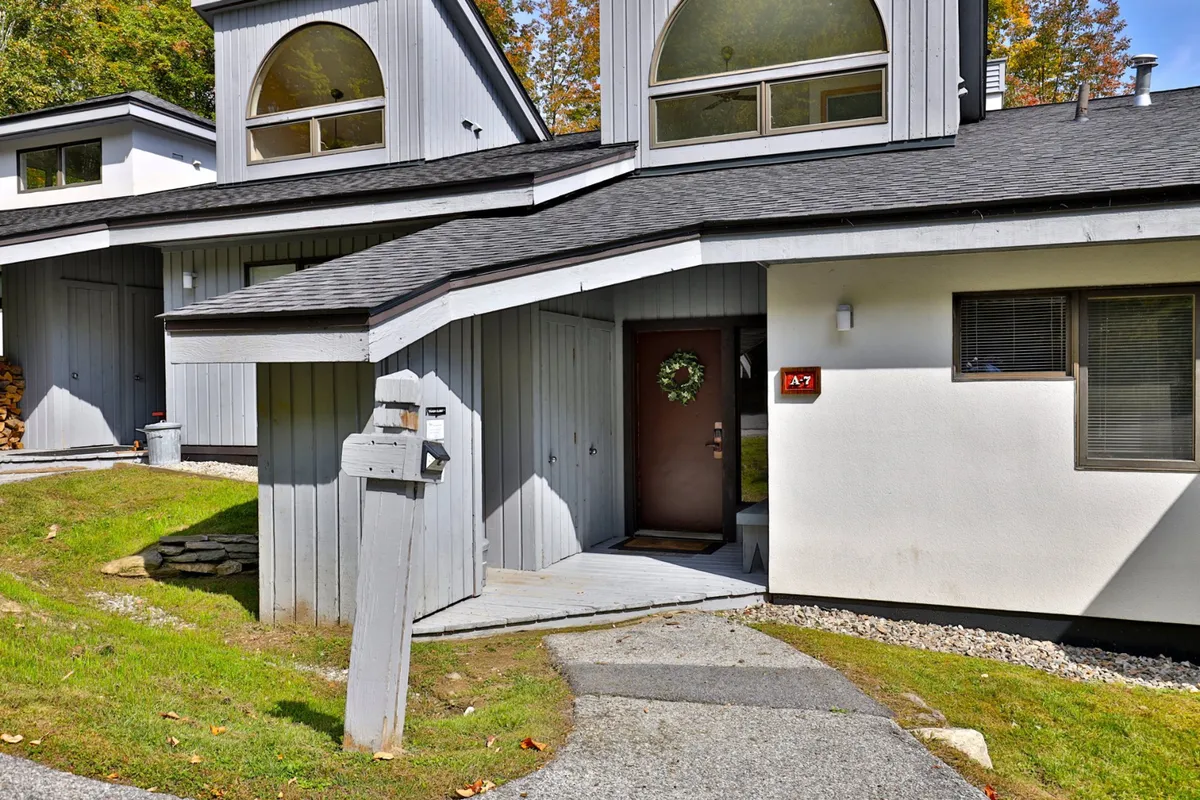 An inviting exterior shot of the condo's front door, adorned with a festive wreath, arched windows, and a welcoming pathway leading to the entrance. Seasonal decorations hint at wintertime charm, while the view offers a sense of arrival and access to outdoor activities.