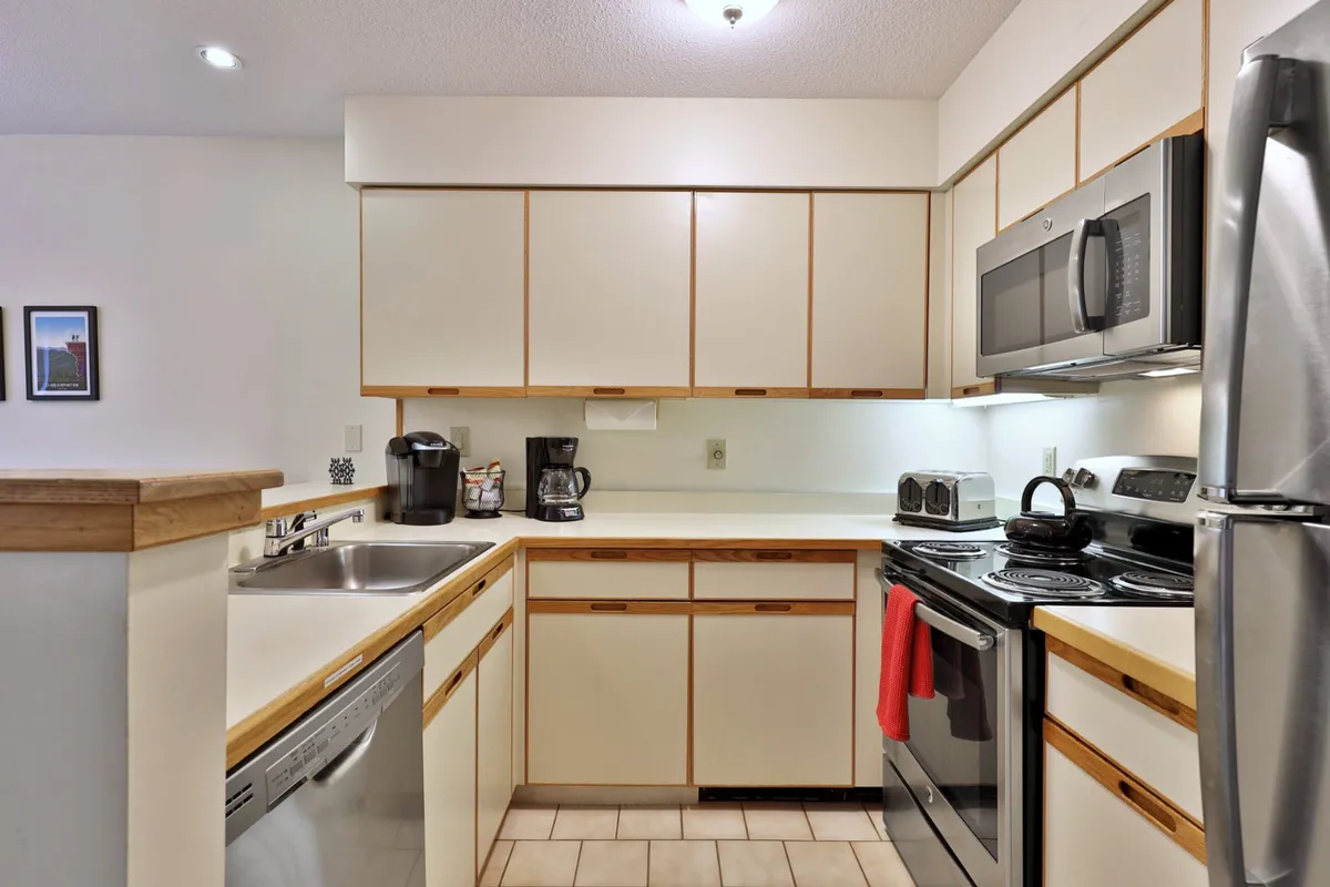 A modern, fully equipped kitchen with stainless steel appliances, a large sink, and ample counter space, exuding warmth and functionality. The room is ready for family cooking sessions or morning coffee together.