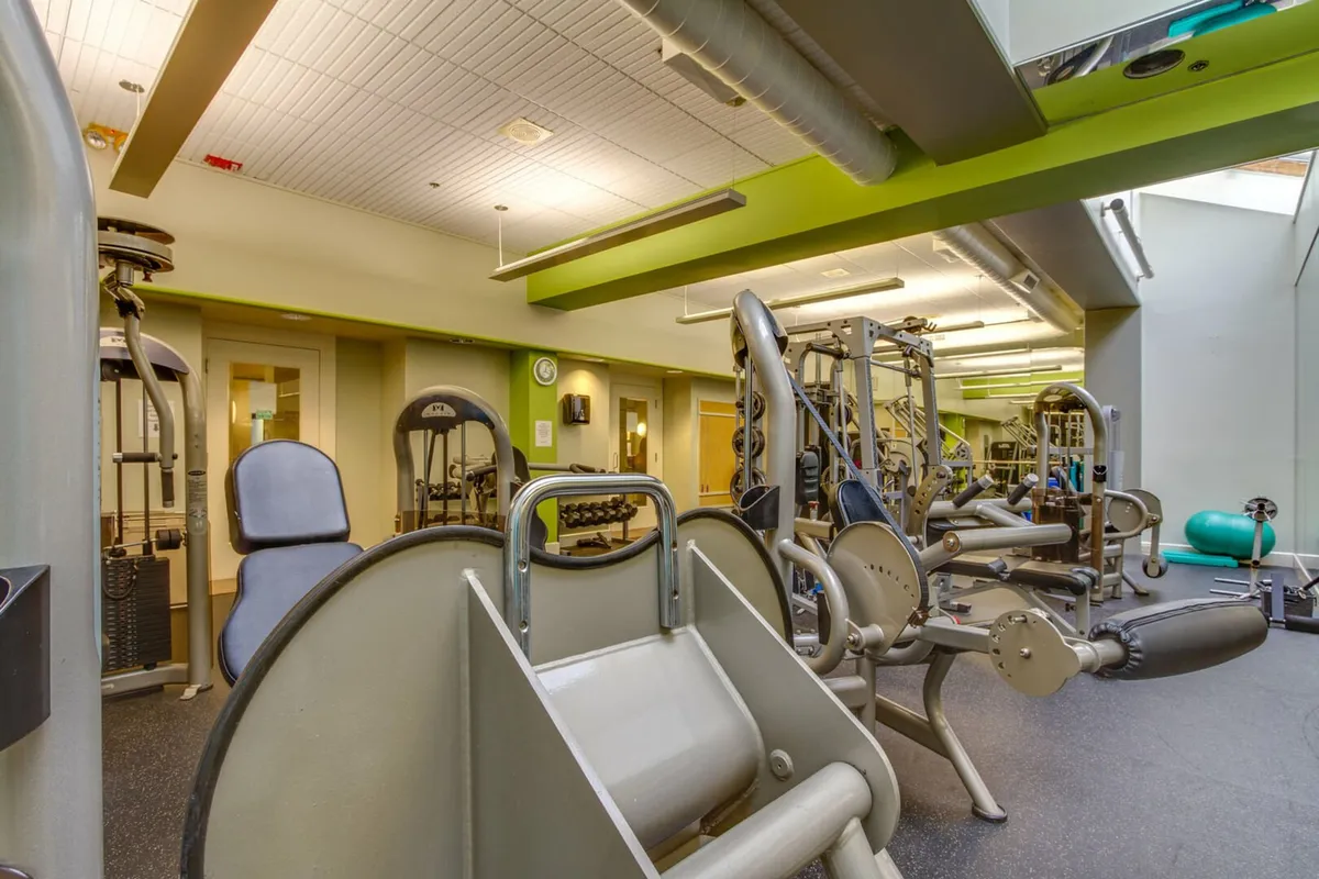 A well-equipped fitness center featuring modern exercise machines, free weights, and a mirrored wall. The open, uncluttered space is designed for both individual workouts and group fitness activities, with ample room for stretching or yoga.