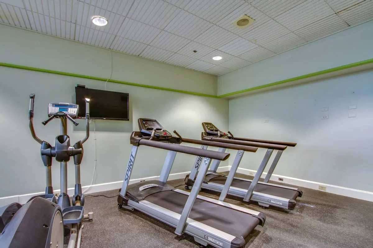 A well-equipped fitness center with treadmills, an elliptical machine, and a television for entertainment. The space is bright and motivational, ideal for both individual workouts and group fitness sessions.