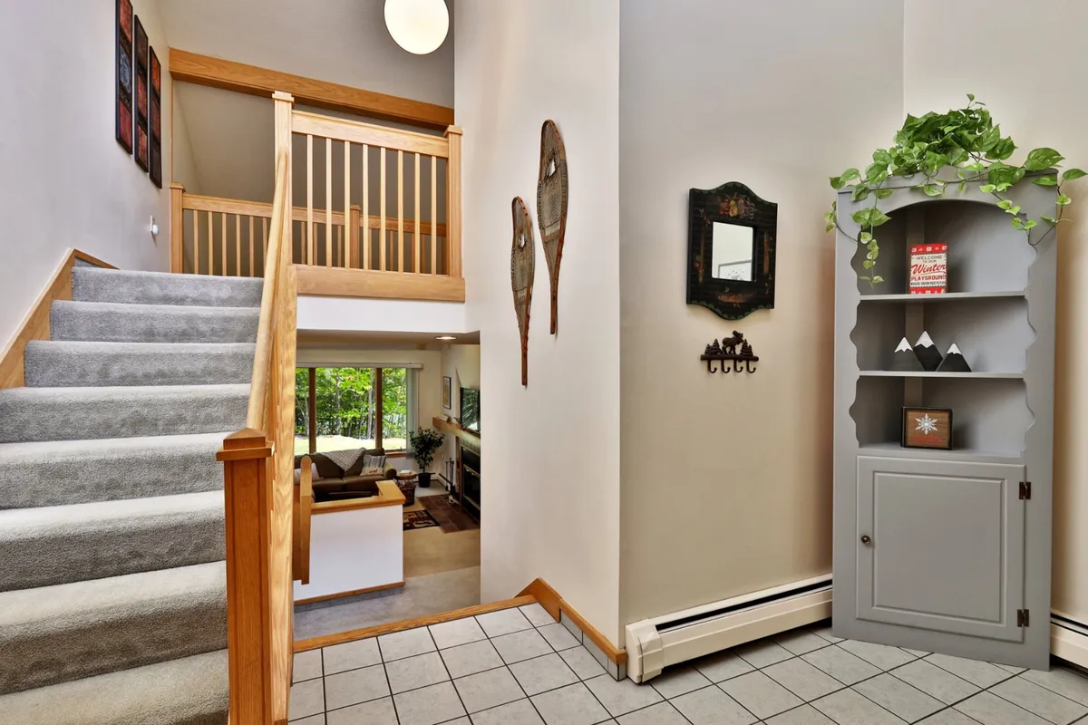 A stylish, inviting foyer featuring a staircase, decorative snowshoes, a mirror, and a shelf adorned with plants. The decor hints at local adventure and tells a story of exploration, making it a memorable first impression for guests.